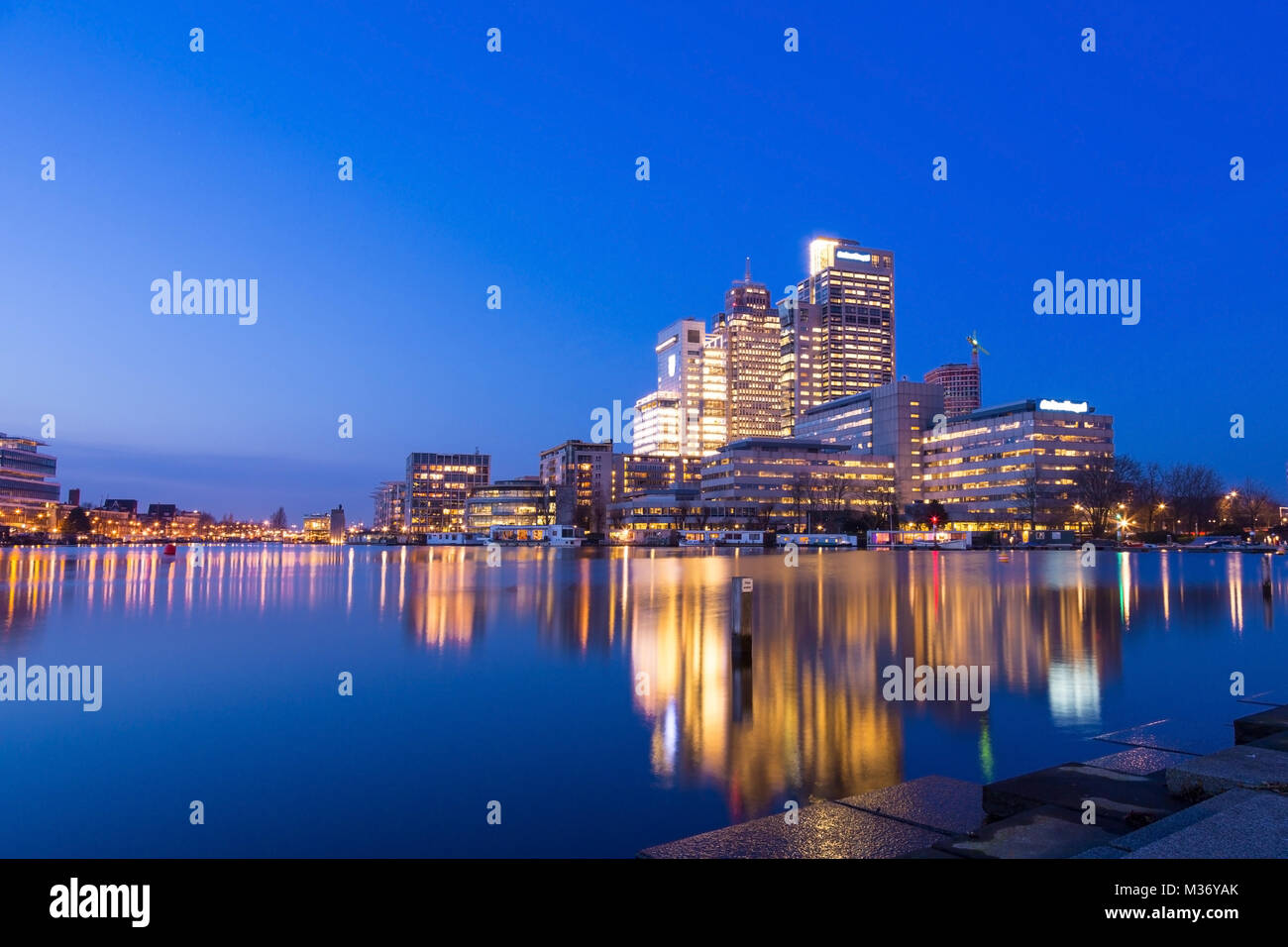 Amsterdam city skyline avec Rembrandt, Breitner et tour de Mondriaan, près de la rivière Amstel au coucher du soleil pendant l'heure bleue avec des reflets dans l'eau. Banque D'Images