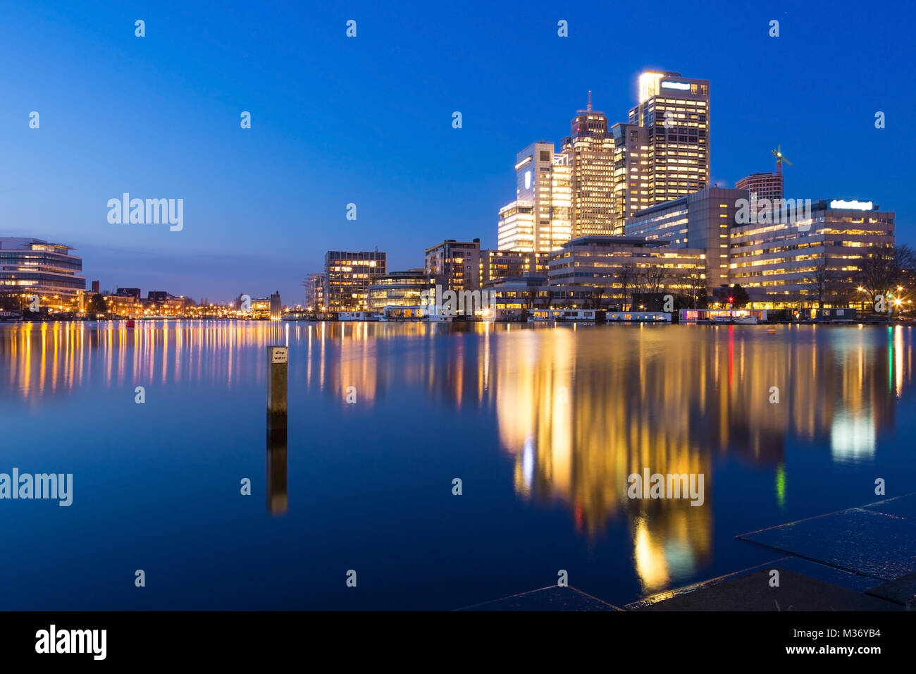 Amsterdam city skyline avec Rembrandt, Breitner et tour de Mondriaan, près de la rivière Amstel au coucher du soleil pendant l'heure bleue avec des reflets dans l'eau. Banque D'Images