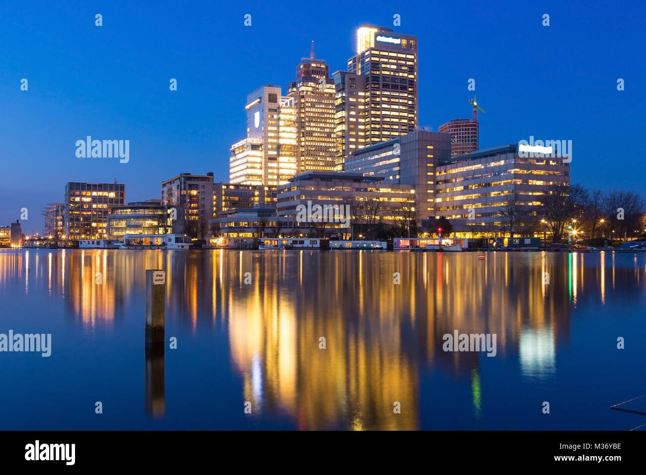 Amsterdam city skyline avec Rembrandt, Breitner et tour de Mondriaan, près de la rivière Amstel au coucher du soleil pendant l'heure bleue avec des reflets dans l'eau. Banque D'Images