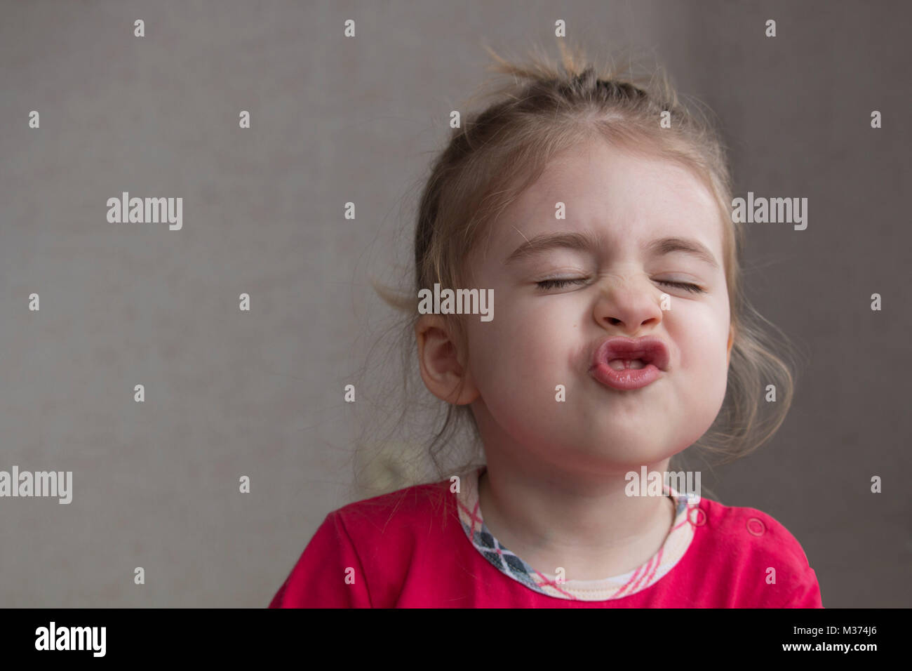 Clouse-up portrait of smiling little girl making funny grimace et gestes à l'appareil photo. Avez-vous souri aujourd'hui Banque D'Images