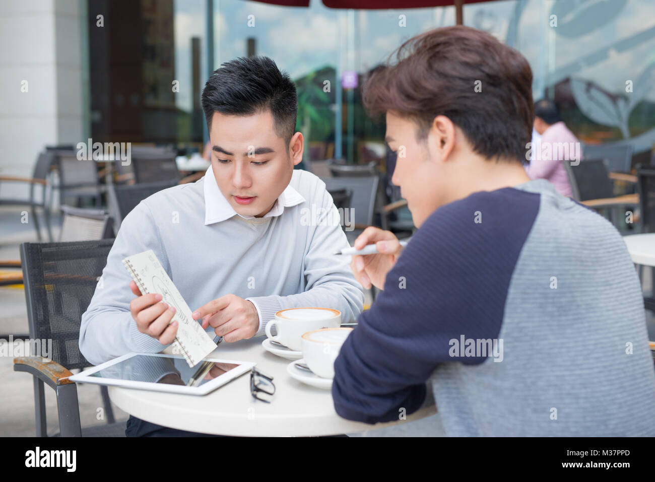 Deux jeunes hommes d'affaires dans les tenues de beau sourire, discuter dans un café. Banque D'Images