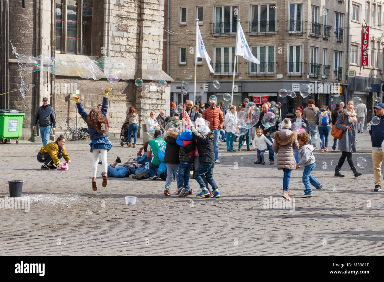 Enfants jouant et s'amusant avec les bulles de savon à la place Saint Nicolas sur une journée ensoleillée. Gand, Belgique. Banque D'Images