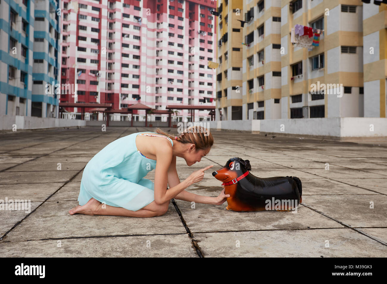 Aimant s'amuser heureux jeune danseuse avec ballon jouet chien à Rochor Centre, Singapour. Ces bâtiments colorés sont monument historique. Banque D'Images