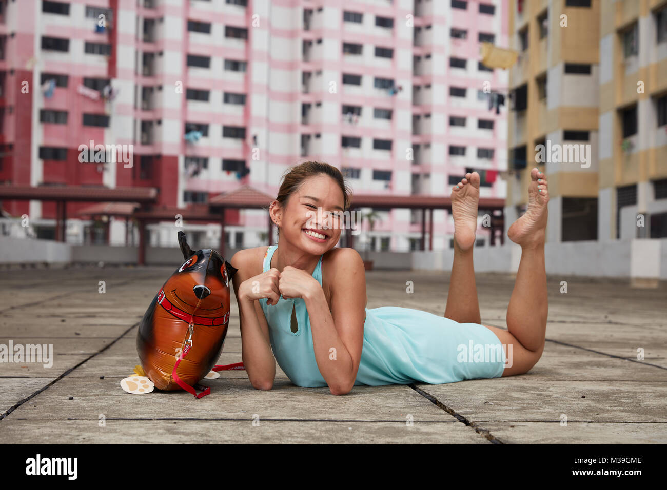Aimant s'amuser heureux jeune danseuse avec ballon jouet chien à Rochor Centre, Singapour. Ces bâtiments colorés sont monument historique. Banque D'Images