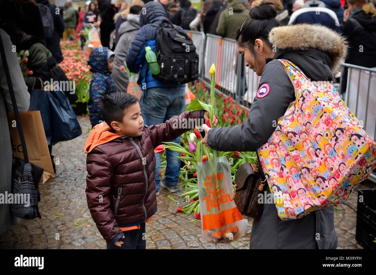 Amsterdam, Pays-Bas - Janvier, 2018 : un jeune garçon fleurs remise à sa mère pendant la journée de la tulipe sur le Dam Square dans le centre-ville Banque D'Images