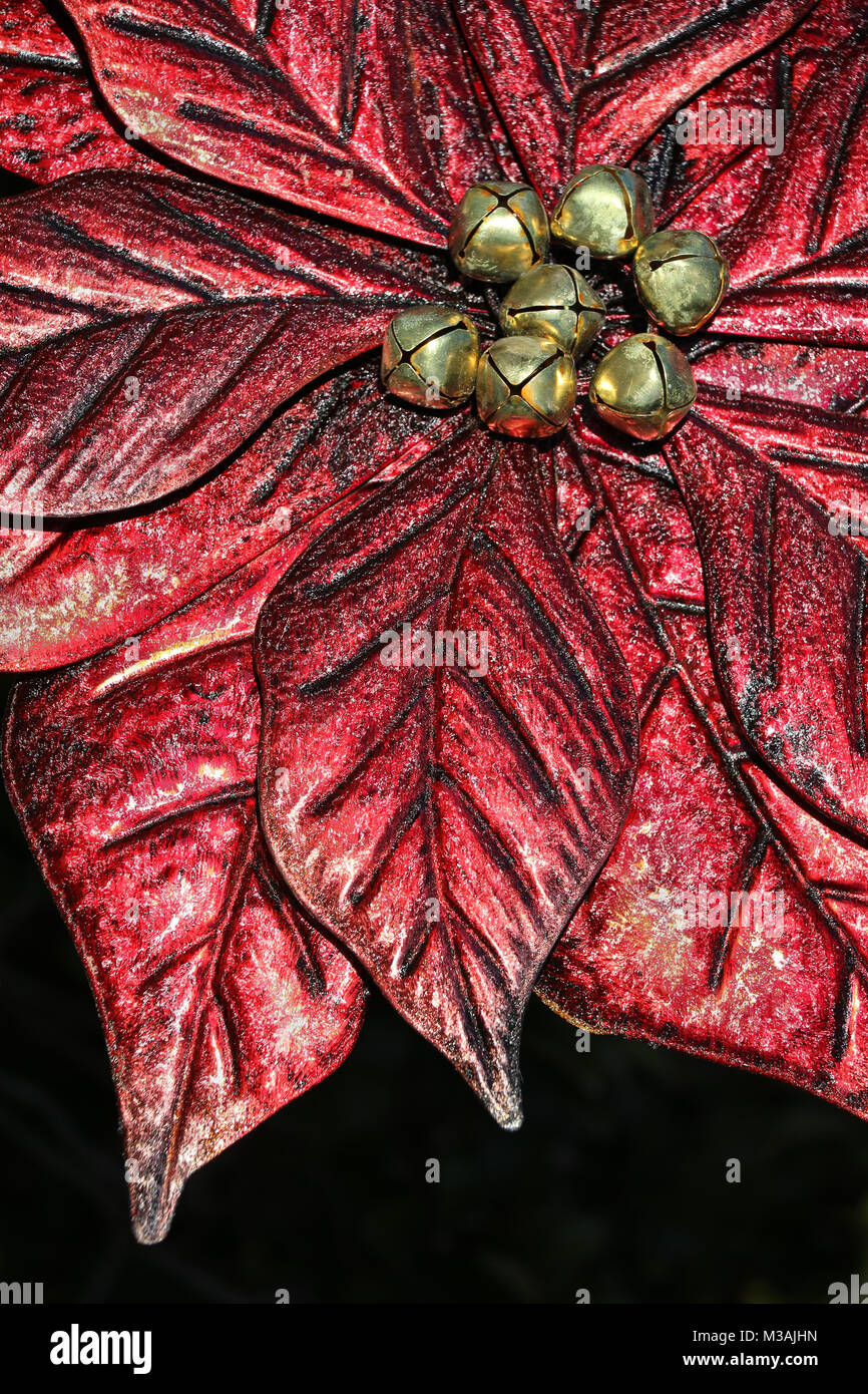 Grand rouge scintillant spectaculaire décoration poinsettia artificiel avec le centre d'or Jingle bells prêt pour Noël sur fond noir Banque D'Images