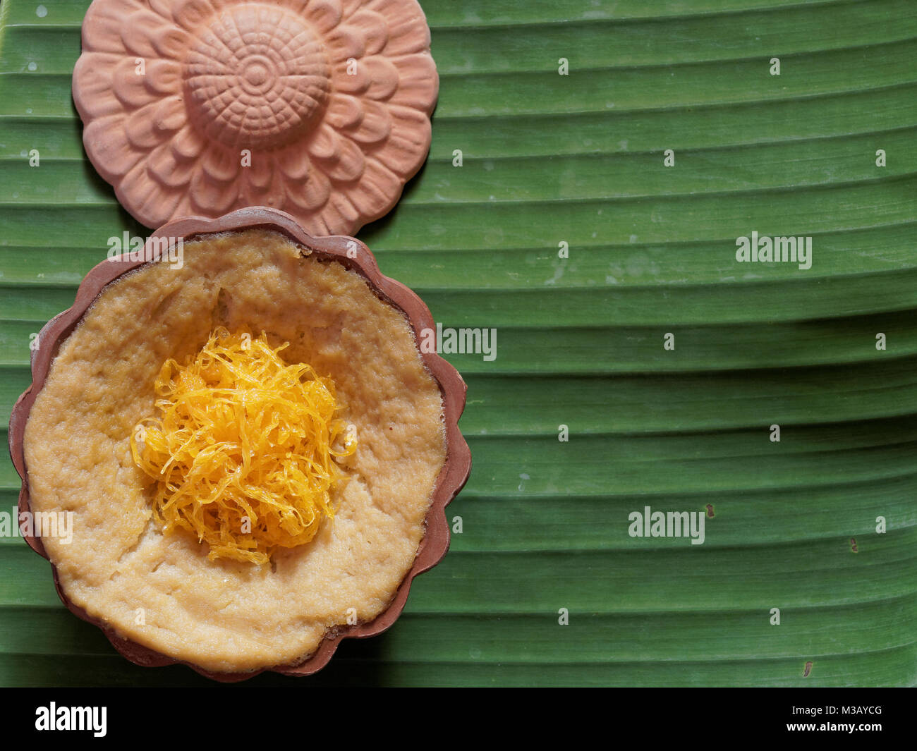 Dessert thaï, crème d'oeufs avec le riz gluant sucré surmonté de fils d'or, sur fond de feuilles de banane Banque D'Images