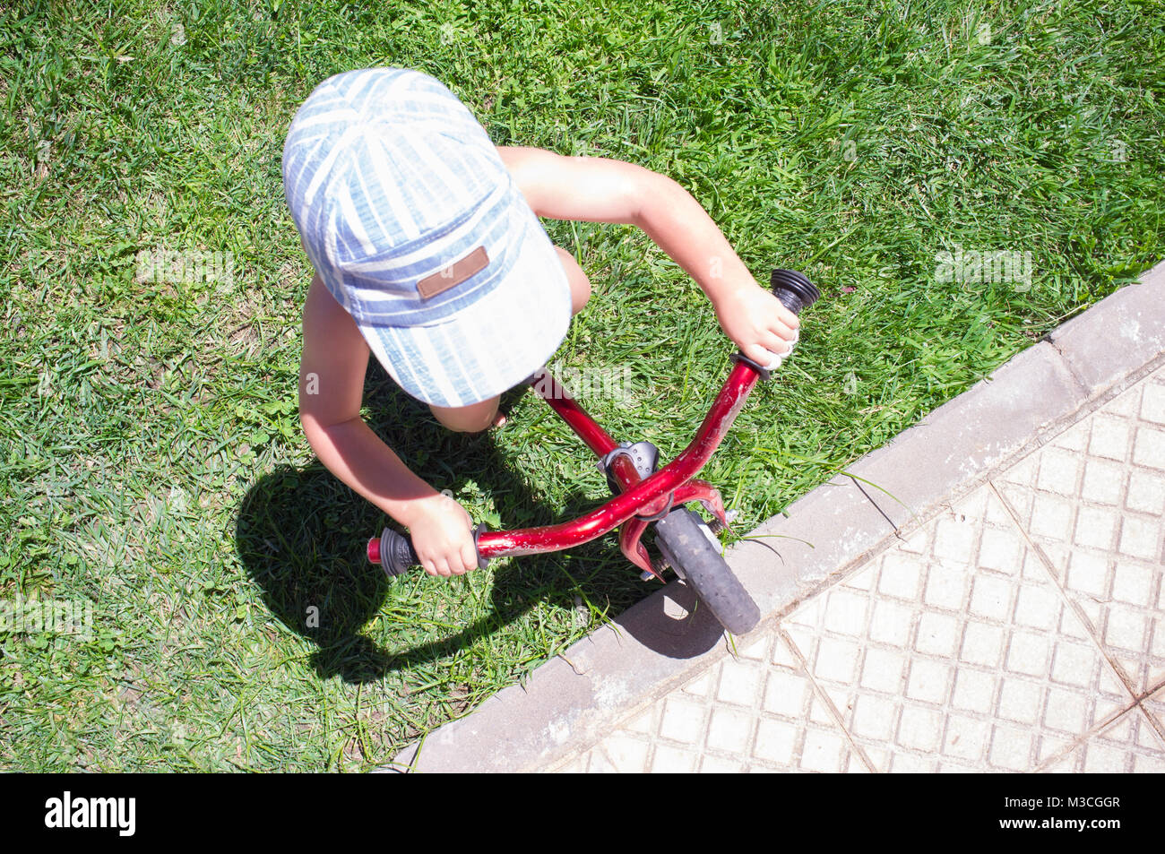 Boy in Blue Cap équitation un vélo équilibre bleu (run bike). Heureux l'enfant apprendre à garder l'équilibre dans le jardin Banque D'Images