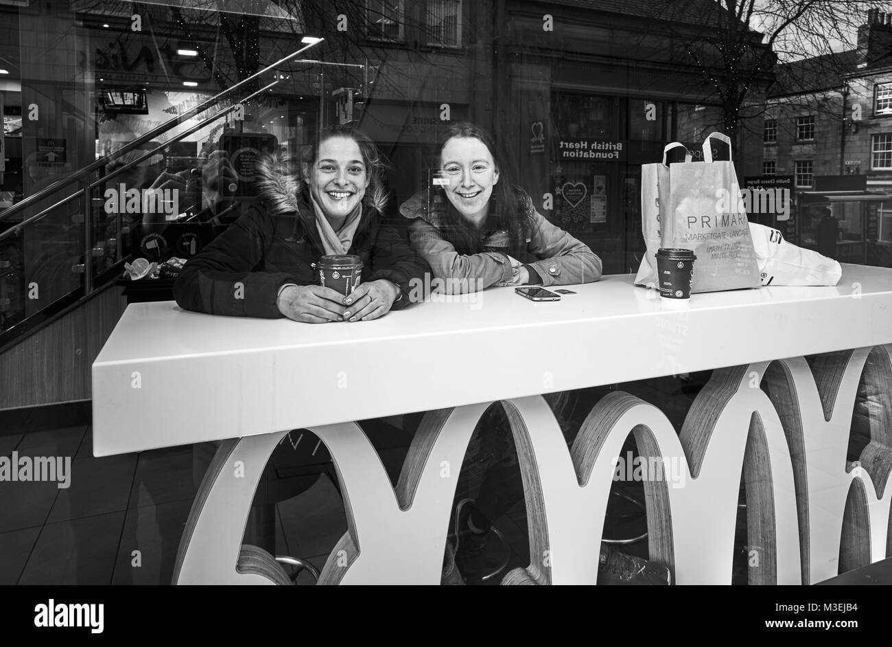 Deux jeunes femmes ayant un café dans la fenêtre à Macdonalds à Lancaster Banque D'Images