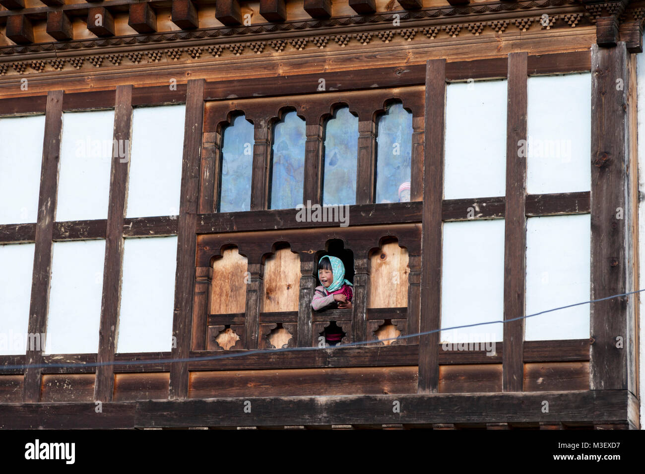 Le Bhoutan, Phobjikha. Jeune fille à la fenêtre de sa chambre, Kikorthang Village. Banque D'Images