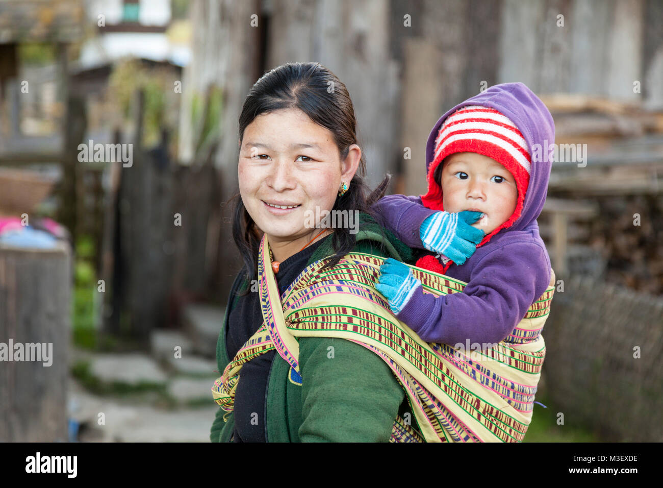 Le Bhoutan, Phobjikha. Femme transportant du jeune enfant à l'arrière, Kikorthang Village. Banque D'Images