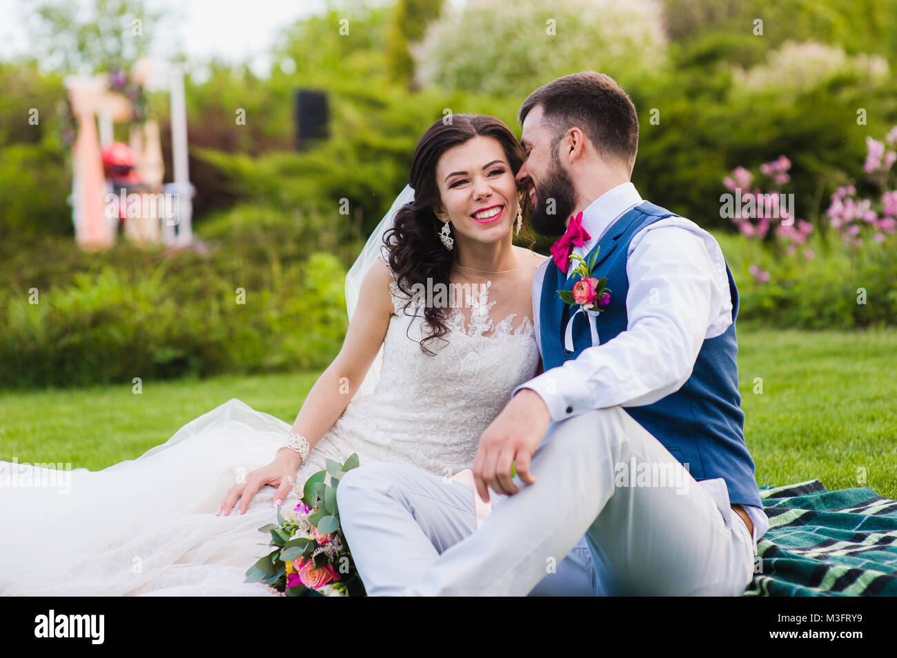 Quelque chose de drôle à dire marié la mariée pendant qu'ils et assis dans le parc verdoyant. Beau couple de rire et plaisanter ensemble à leur mariage da Banque D'Images