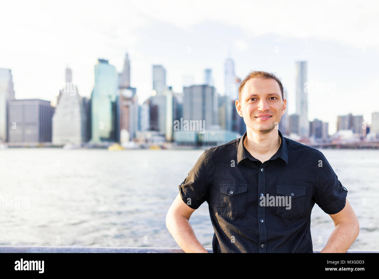 Jeune homme à l'extérieur extérieur dans NYC New York City Pont de Brooklyn Park par East River, garde-corps, à la vue des toits de la ville Banque D'Images