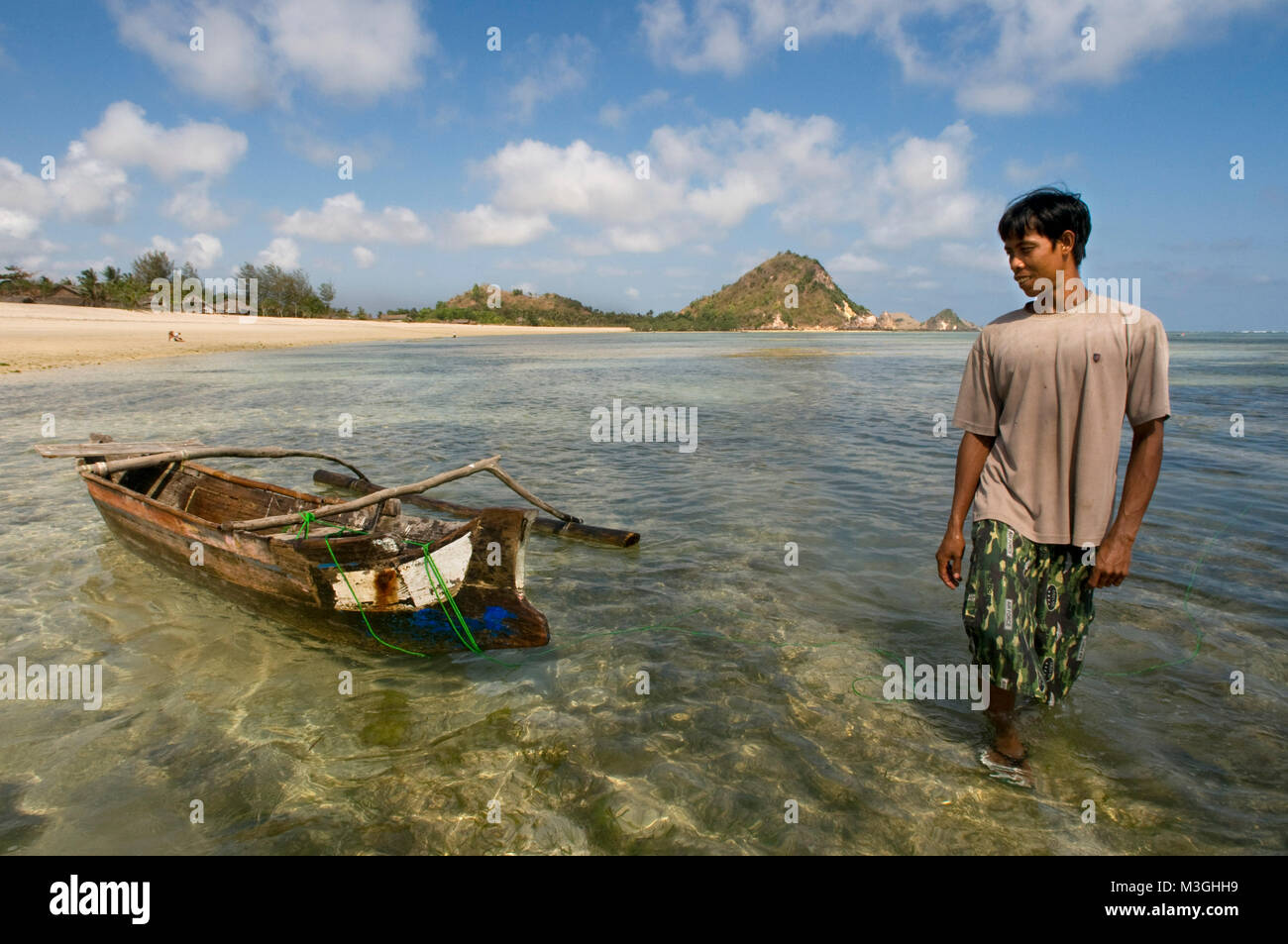 Un pêcheur à côté de son bateau sur les rives de la plage de Kuta, un village de pêcheurs au sud de Lombok, Indonésie Banque D'Images
