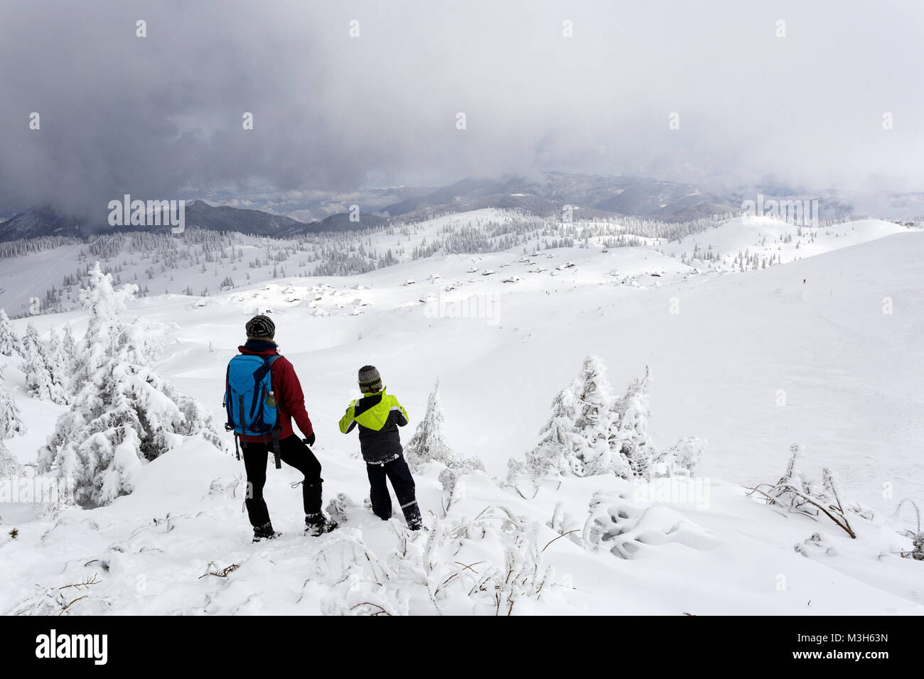 La mère et le fils debout sur le sommet d'une montagne couverte de neige à la recherche jusqu'à la vallée, Velika planina, la Slovénie. Banque D'Images