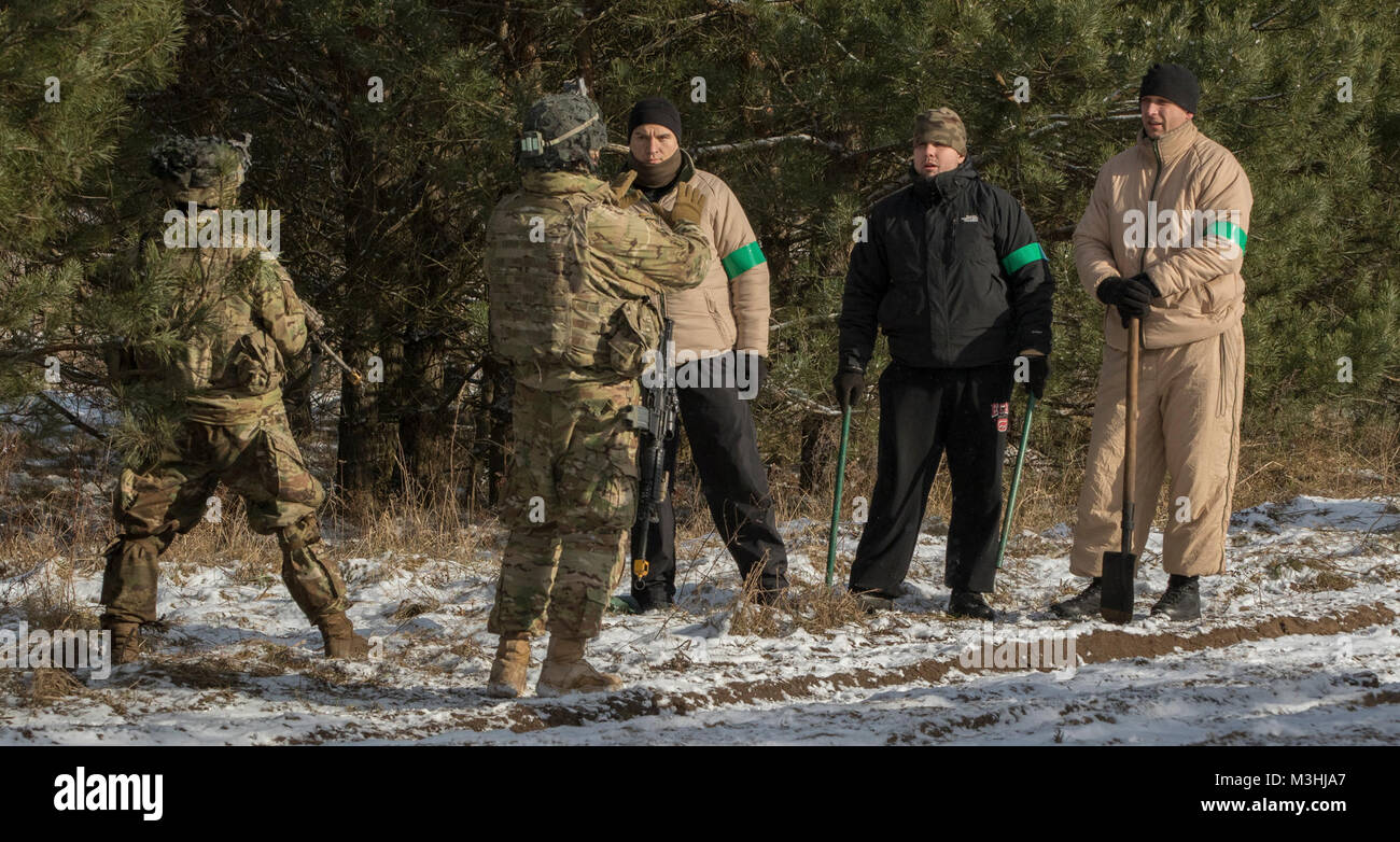 Des soldats américains affectés à la foudre Troop, 3e Escadron, 2e régiment de cavalerie, effectuer une situation fondée sur des scénarios avec des soldats polonais agissant en qualité de civils au cours de l'exercice de poste de commandement près de la Belette Bemowo Piskie Domaine de formation, Pologne, le 6 février 2018. Ces soldats sont une partie de l'unique groupe de combat, multinationale, composée d'Américains, Britanniques, croate et soldats roumains servir avec la 15e Brigade mécanisée polonaise comme une force de dissuasion dans le nord-est de la Pologne à l'appui de l'OTAN vers l'amélioration de la présence. (U.S. Army Banque D'Images