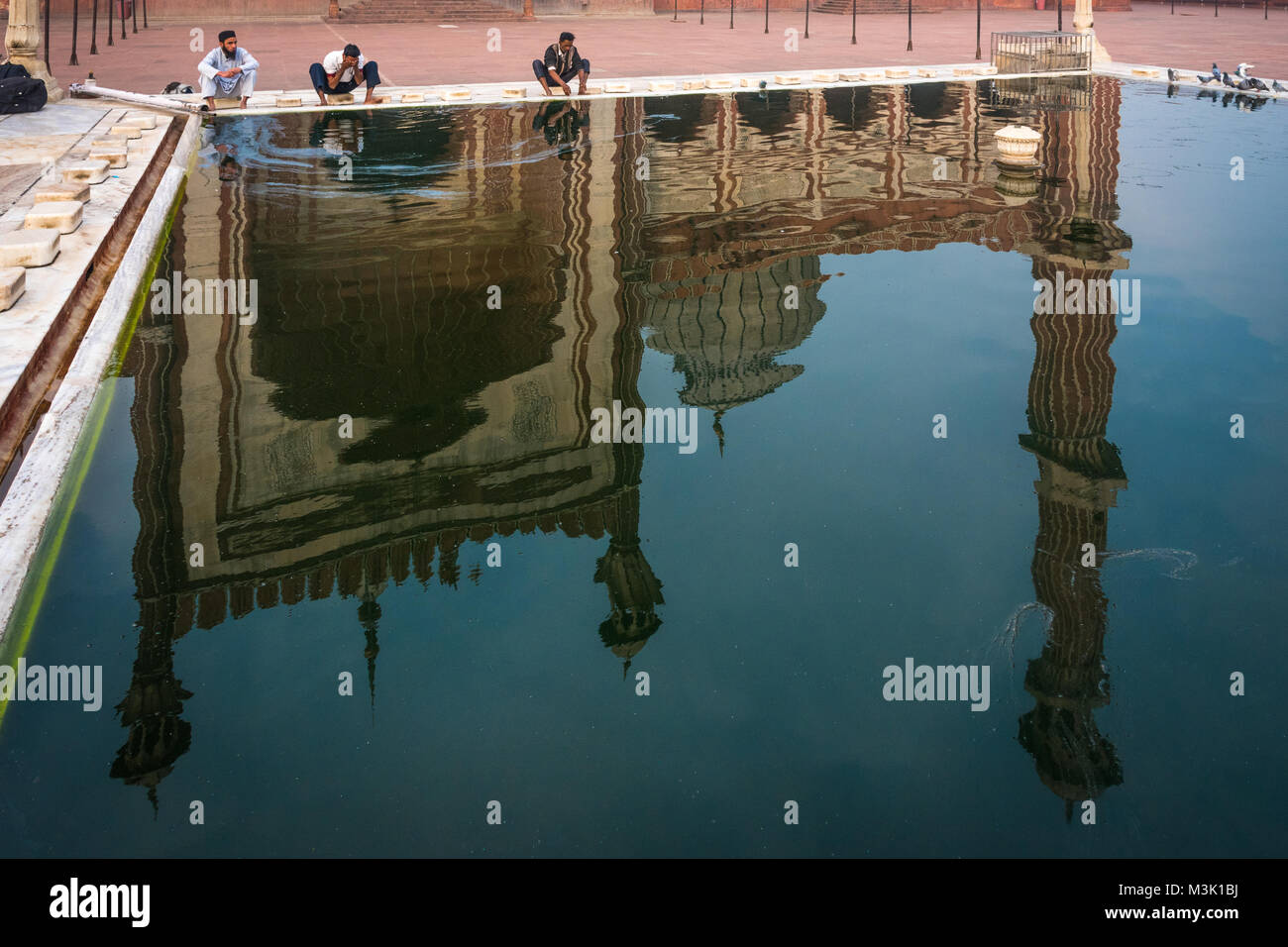 Les pèlerins et les reflets dans l'étang à Jama Masjid, Delhi, Inde. Banque D'Images