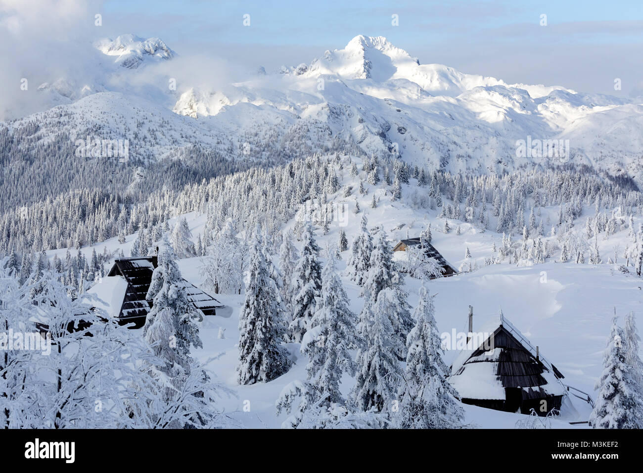 Vue panoramique de cabines en bois couvert de neige et les montagnes atforest Velika planina, la Slovénie. Banque D'Images