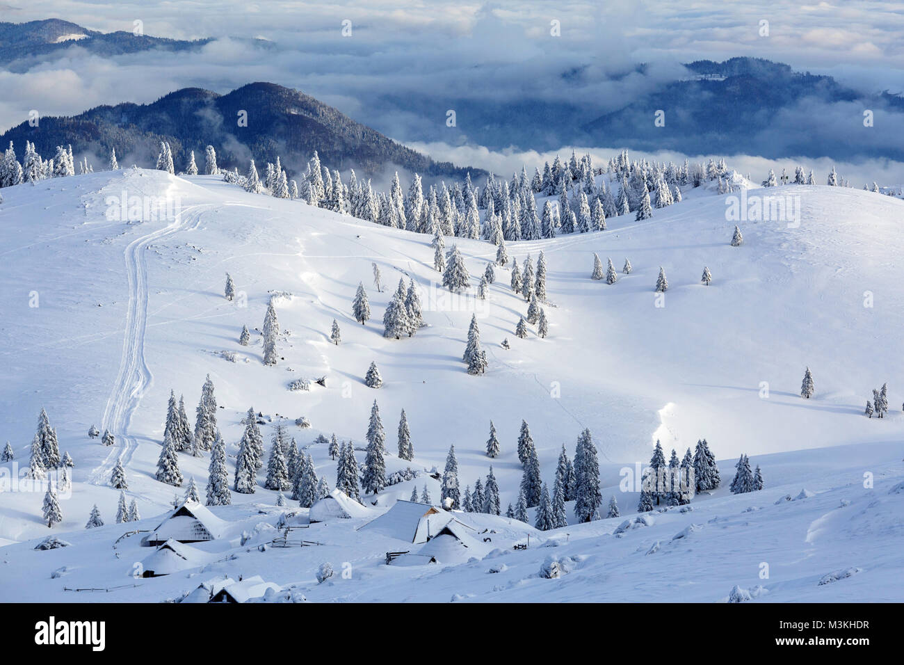 Vue panoramique de cabines en bois couvert de neige et les montagnes et la forêt Velika planina, la Slovénie. Banque D'Images