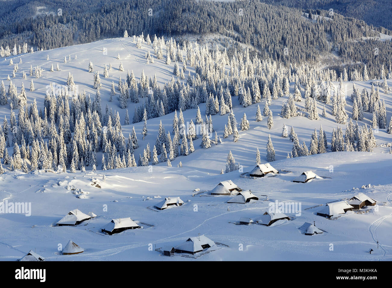 Vue panoramique de cabines en bois couvert de neige et les montagnes et la forêt Velika planina, la Slovénie. Banque D'Images