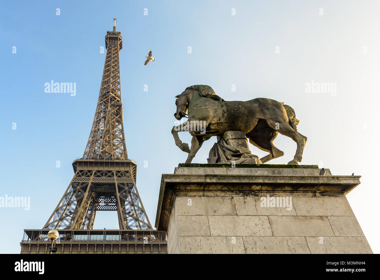 Low angle view of la Tour Eiffel à Paris, vu depuis le pont d'Iéna contre le ciel bleu, avec un equestrian statue en pierre au premier plan. Banque D'Images