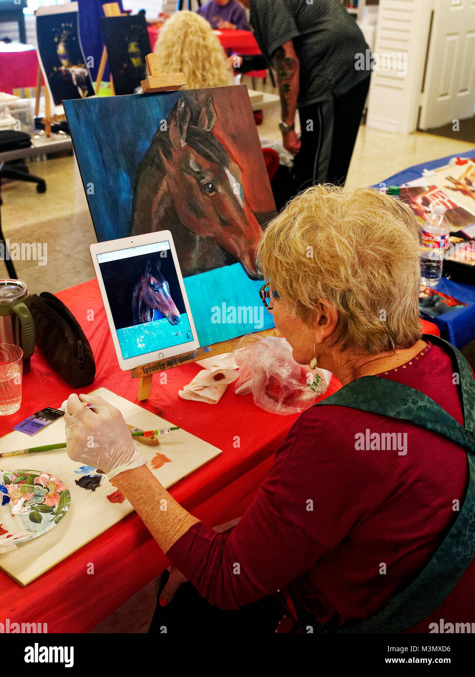 Les aînés ayant vécu une longue dure toujours demeurer actif s'exprimer en classe de peinture, Pam Smith utilise une photo prise avec son iPad pour peindre un cheval d'amis. Banque D'Images