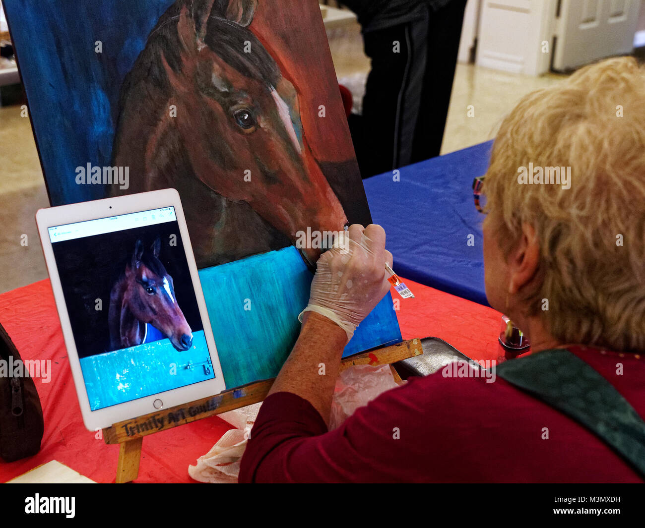 Les aînés ayant vécu une longue dure toujours demeurer actif s'exprimer en classe de peinture, Pam Smith utilise une photo prise avec son iPad pour peindre un cheval d'amis. Banque D'Images