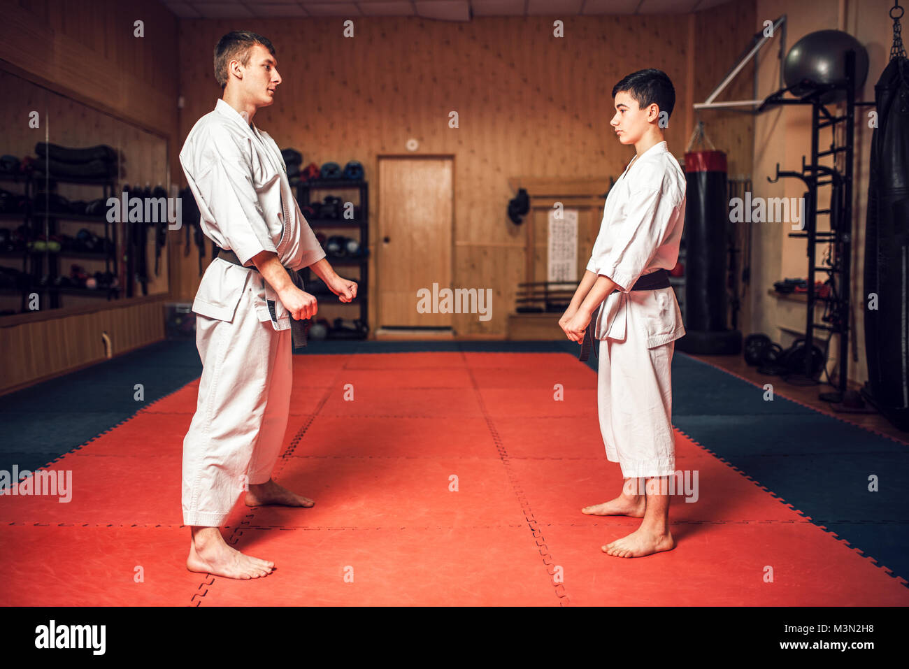 Arts martiaux karate master et jeune disciple en uniforme blanc et les ceintures noires sur la formation en salle de sport Banque D'Images