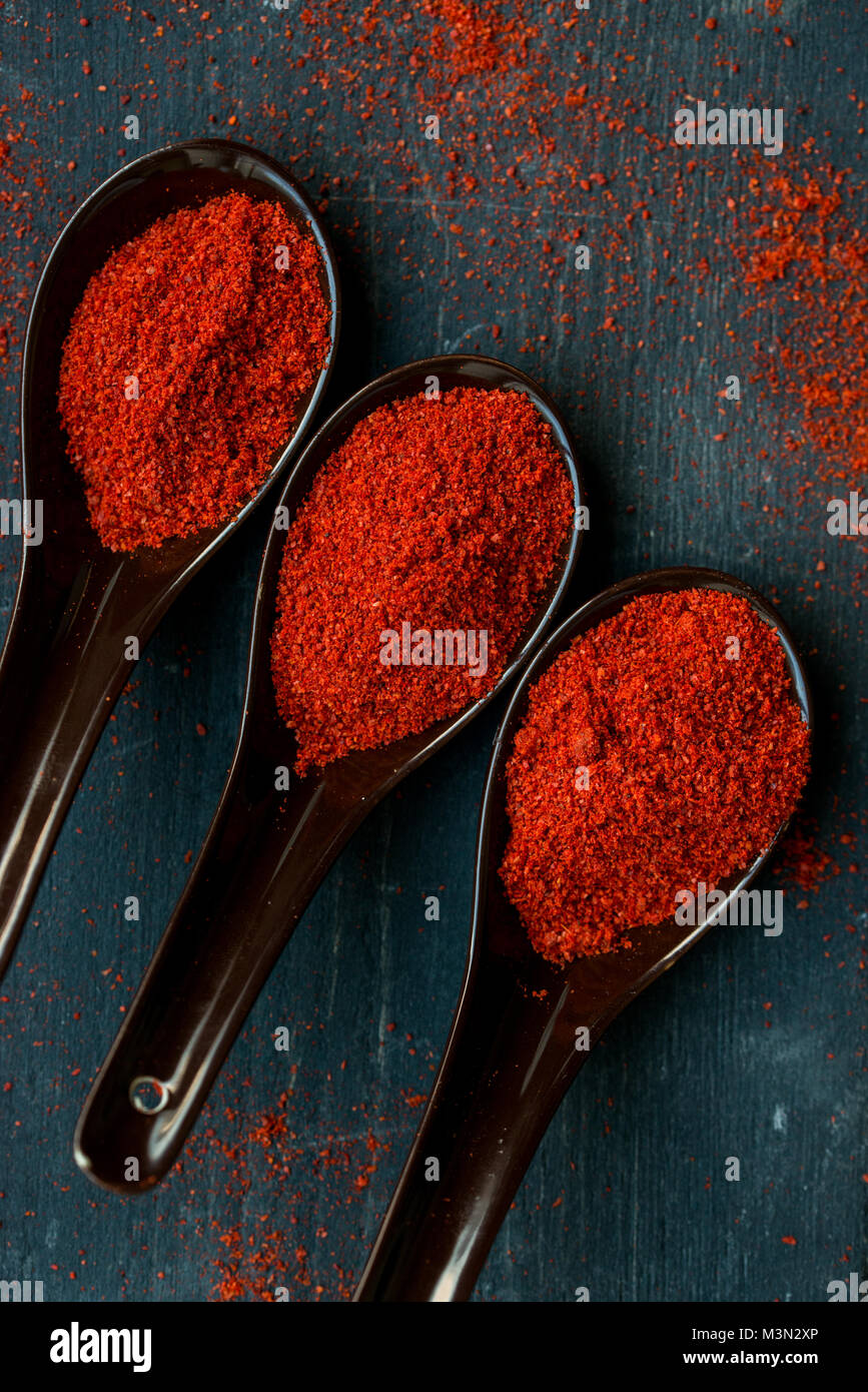Vue de dessus trois cuillères en plastique remplis d'épices paprika rouge foncé sur fond de bois Banque D'Images Vue de dessus trois cuillères en plastique remplis d'épices paprika rouge foncé sur fond de bois Banque D'Images