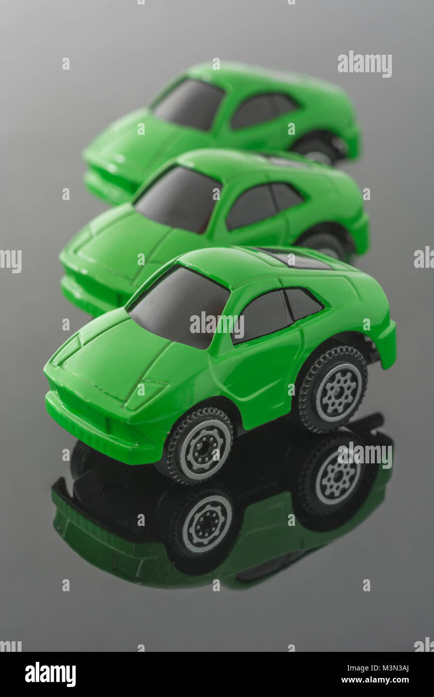Trois voitures jouets vert sur fond réfléchissant. Métaphore Green cars,  les véhicules Tesla, empreinte carbone, taxe sur les véhicules, véhicules  électriques, AOC Green New Deal Photo Stock - Alamy