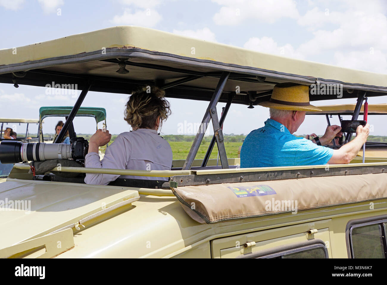 Tourist sur safari dans le Serengeti de Tanzanie en tenant un téléphone cellulaire avec selfies appareil photo. Banque D'Images