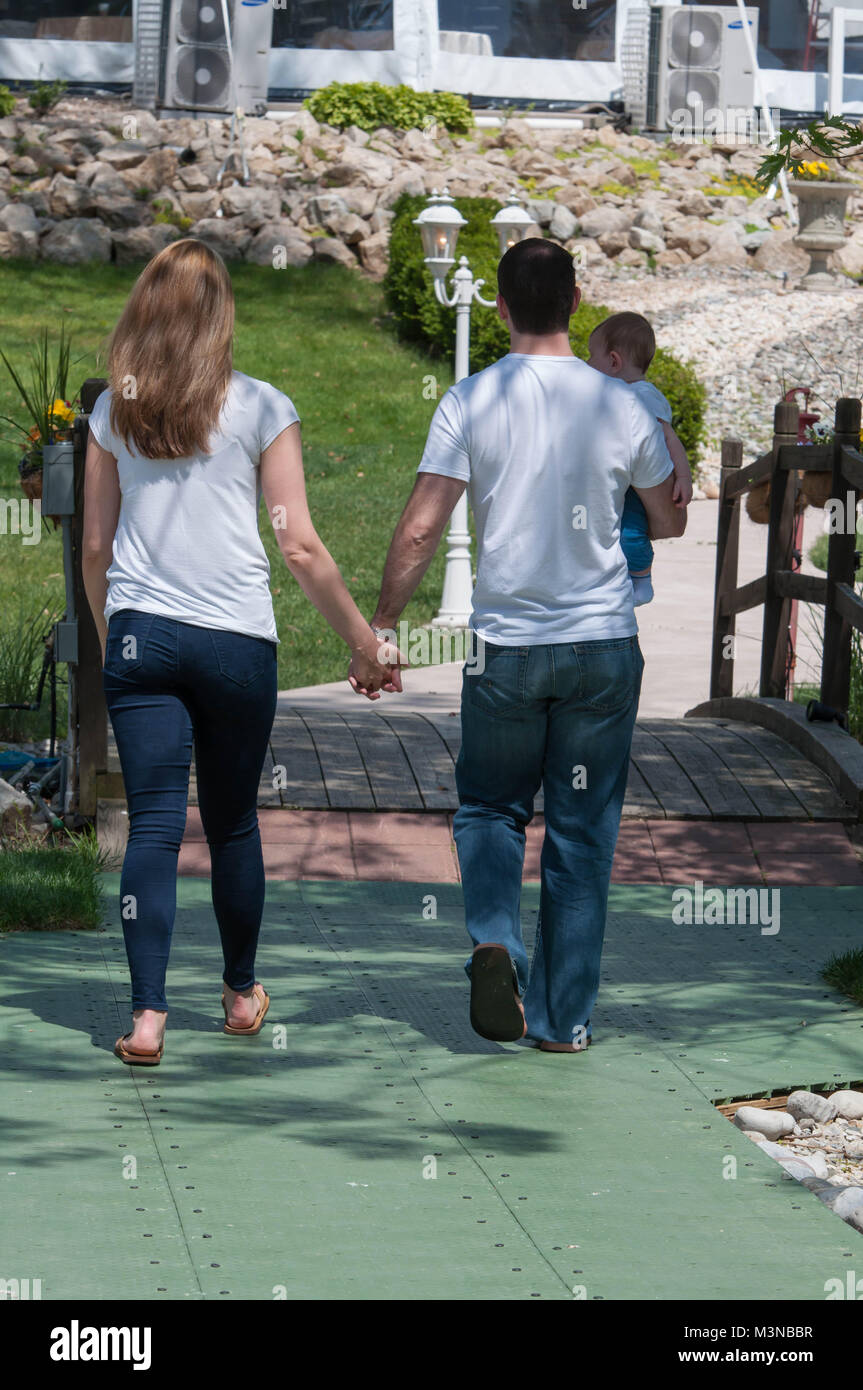 Married Couple Holding Hands et transportant Enfant Banque D'Images