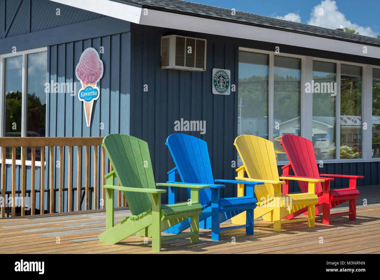 Les couleurs vives des chaises Adirondack sur terrasse en bois extérieur magasin concession café Starbucks signe journée ensoleillée Georgian Bay Parry Sound Ontario Canada Banque D'Images