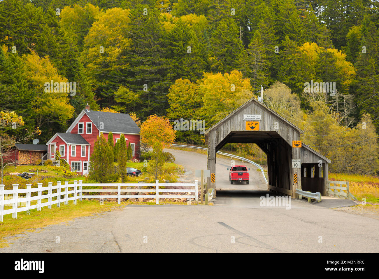 Les arbres d'automne jaune coloré pittoresque vieux pont couvert en bois surround par maison rouge rural St Martins Baie de Fundy, Nouveau-Brunswick Canada Banque D'Images