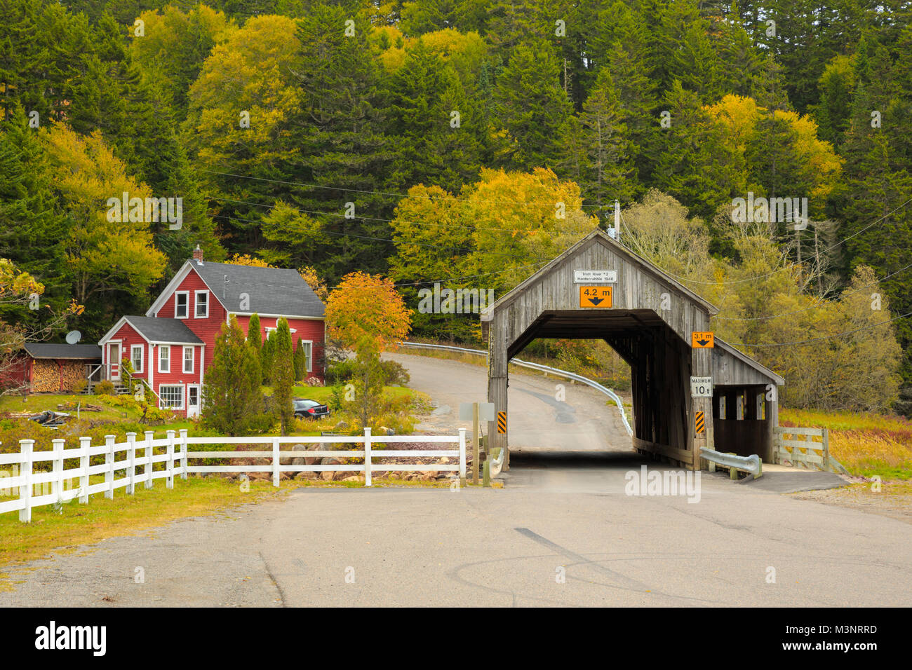 Les arbres d'automne jaune coloré pittoresque vieux pont couvert en bois surround par maison rouge rural St Martins Baie de Fundy, Nouveau-Brunswick Canada Banque D'Images