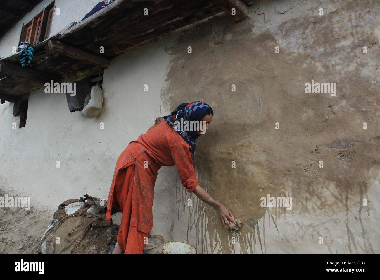 Femme du Cachemire l'application de la bouse de vache sur les murs, kupwara, Cachemire, Inde, Asie Banque D'Images