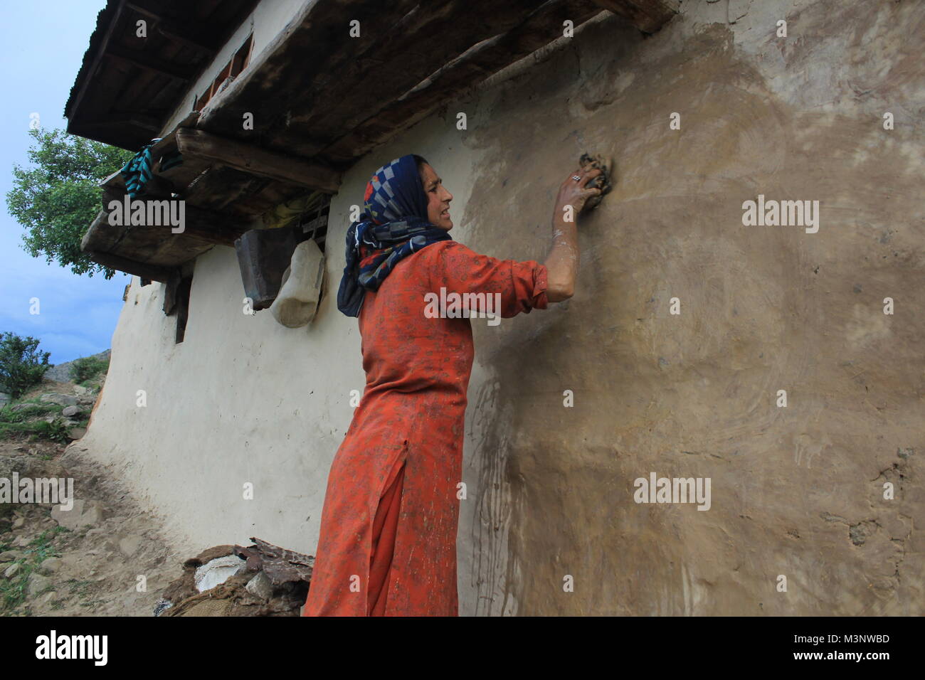 Femme du Cachemire l'application de la bouse de vache sur les murs, kupwara, Cachemire, Inde, Asie Banque D'Images