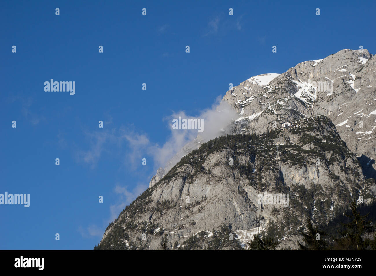Petit chalet autrichien traditionnel perché au sommet d'une falaise massive dans les Alpes Banque D'Images