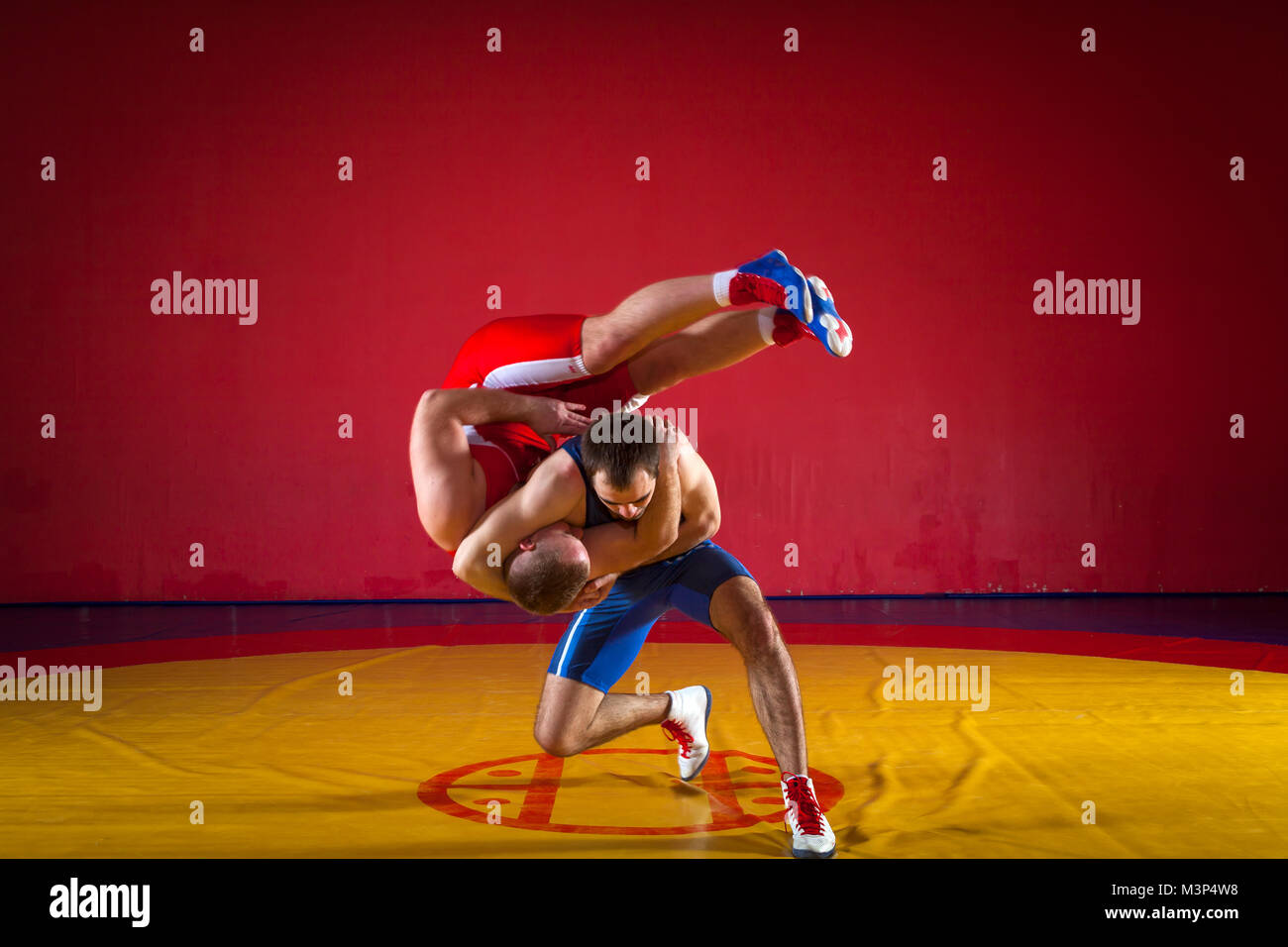 Deux lutteurs gréco-romain en rouge et bleu sur un uniforme jaune wrestling lutte tapis dans la salle de sport Banque D'Images