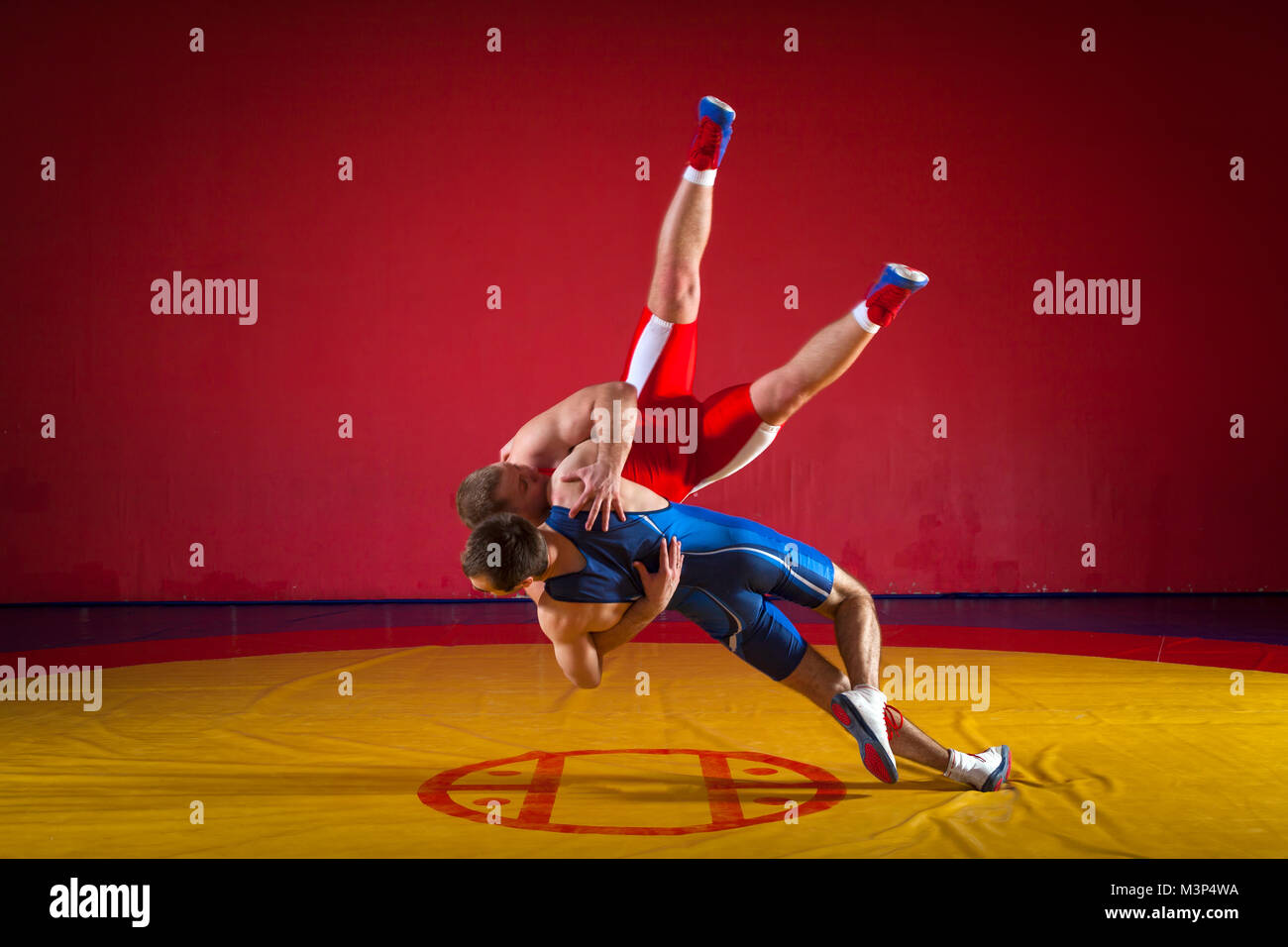 Deux lutteurs gréco-romain en rouge et bleu sur un uniforme jaune wrestling lutte tapis dans la salle de sport Banque D'Images