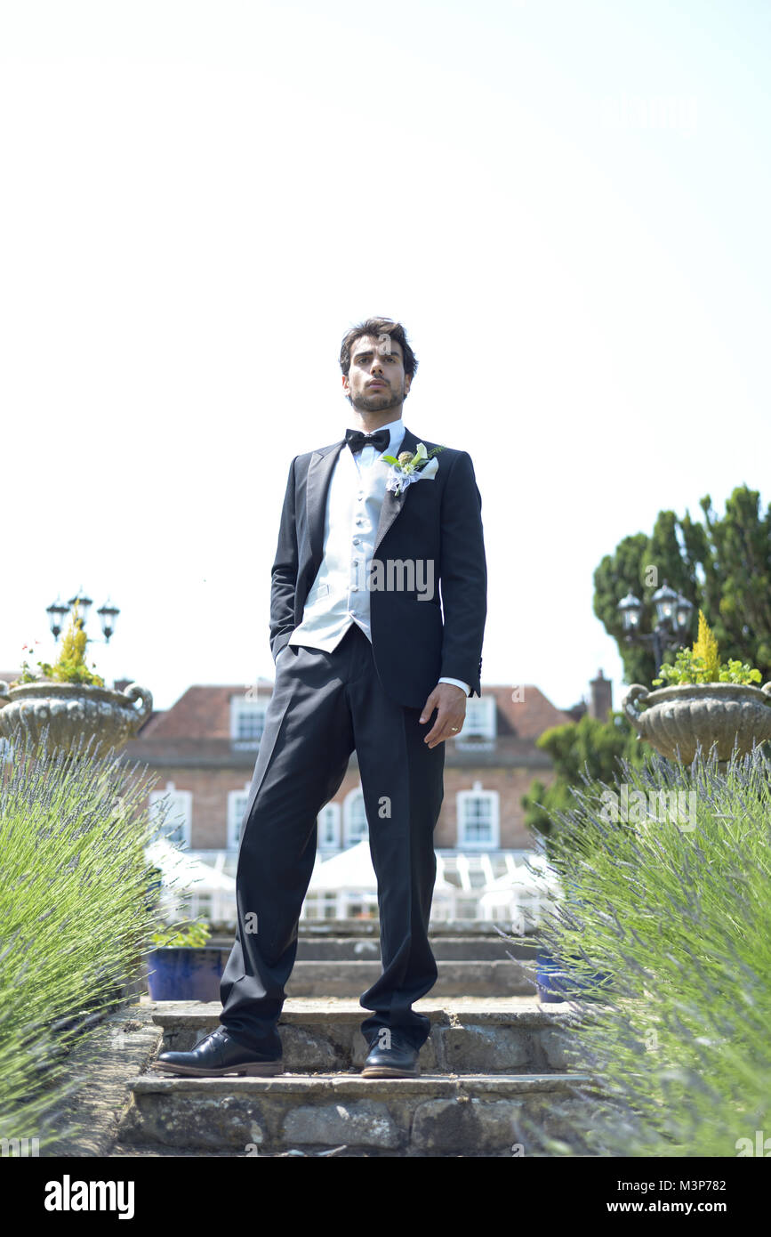 Portrait d'un beau jeune homme aux cheveux noirs en habit de noces sur une journée ensoleillée, il a l'air confiant et heureux Banque D'Images