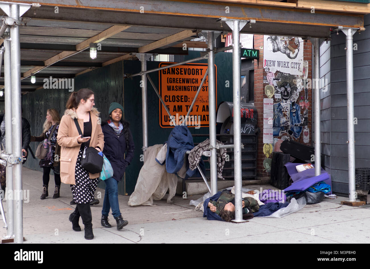 Sans-abri endormi sur le trottoir dans la rue de Manhattan après avoir fait une maison dans le cadre de la construction d'échafaudage des poteaux. Banque D'Images
