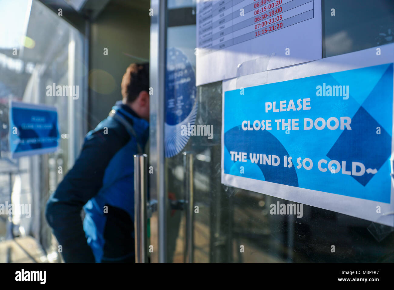 Pyeongchang, Corée du Sud. 12 Février, 2018. Un panneau indique 'Veuillez fermer la porte. Le vent est tellement froid' à l'entrée du centre de presse à l'Alpensia Pyeongchang en centre de saut à ski, de Corée du Sud, 12 février 2018. Crédit : Daniel Karmann/dpa/Alamy Live News Banque D'Images