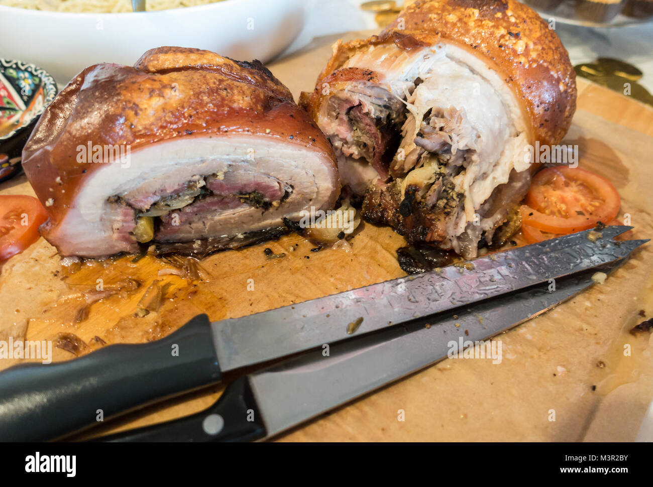 Joints de rôti de porc sur une planche avec deux couteaux à découper. Banque D'Images