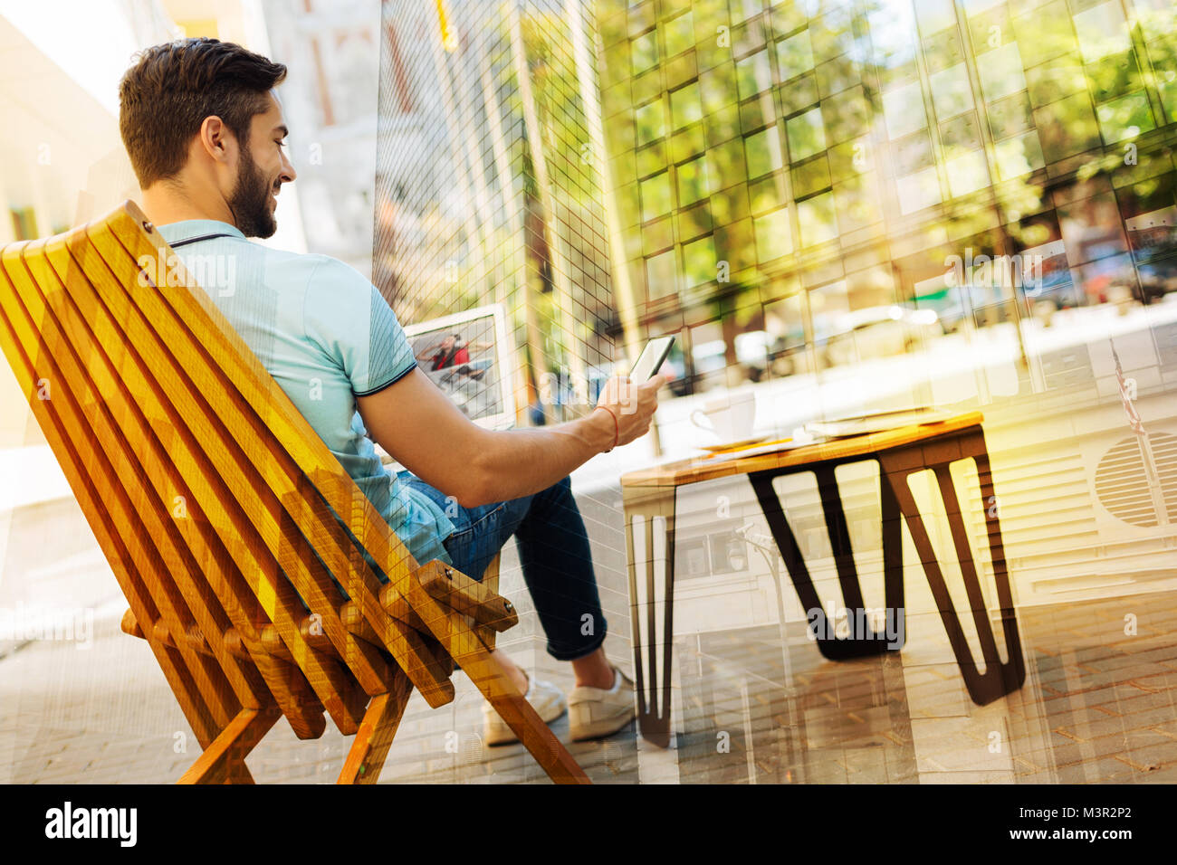 Un homme assis avec deux appareils tout en vous relaxant dans un café Banque D'Images