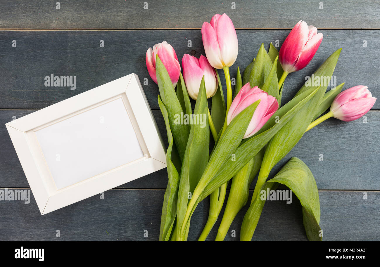 La fête des mères. Bouquet de tulipes roses et un cadre blanc vide bleu sur fond de bois, copie espace, vue du dessus Banque D'Images