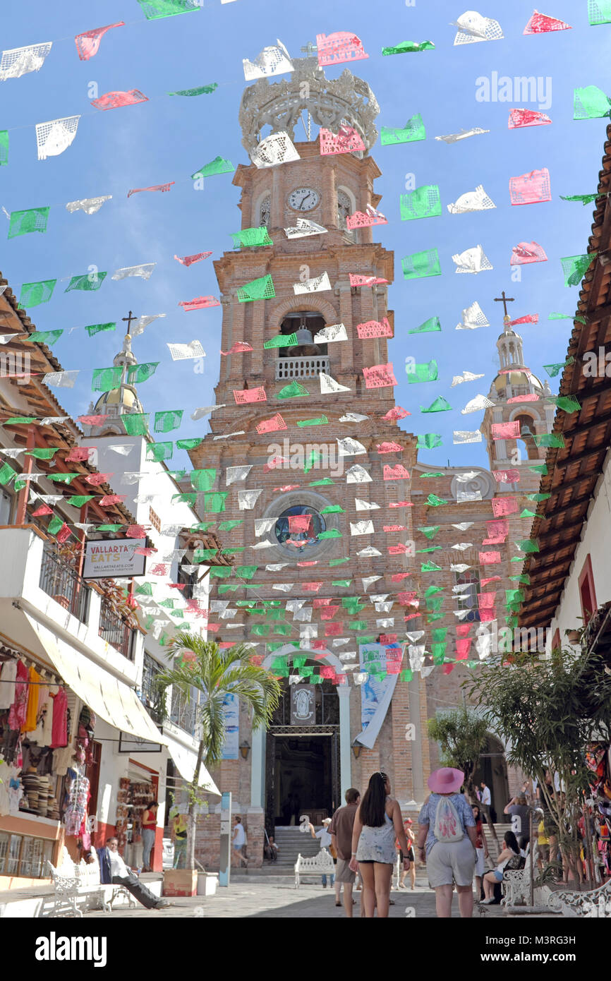 Papel picado drapeaux volent au-dessus de la rue piétonne menant à l'emblématique Église de Notre Dame de Guadalupe à Puerto Vallarta, au Mexique. Banque D'Images