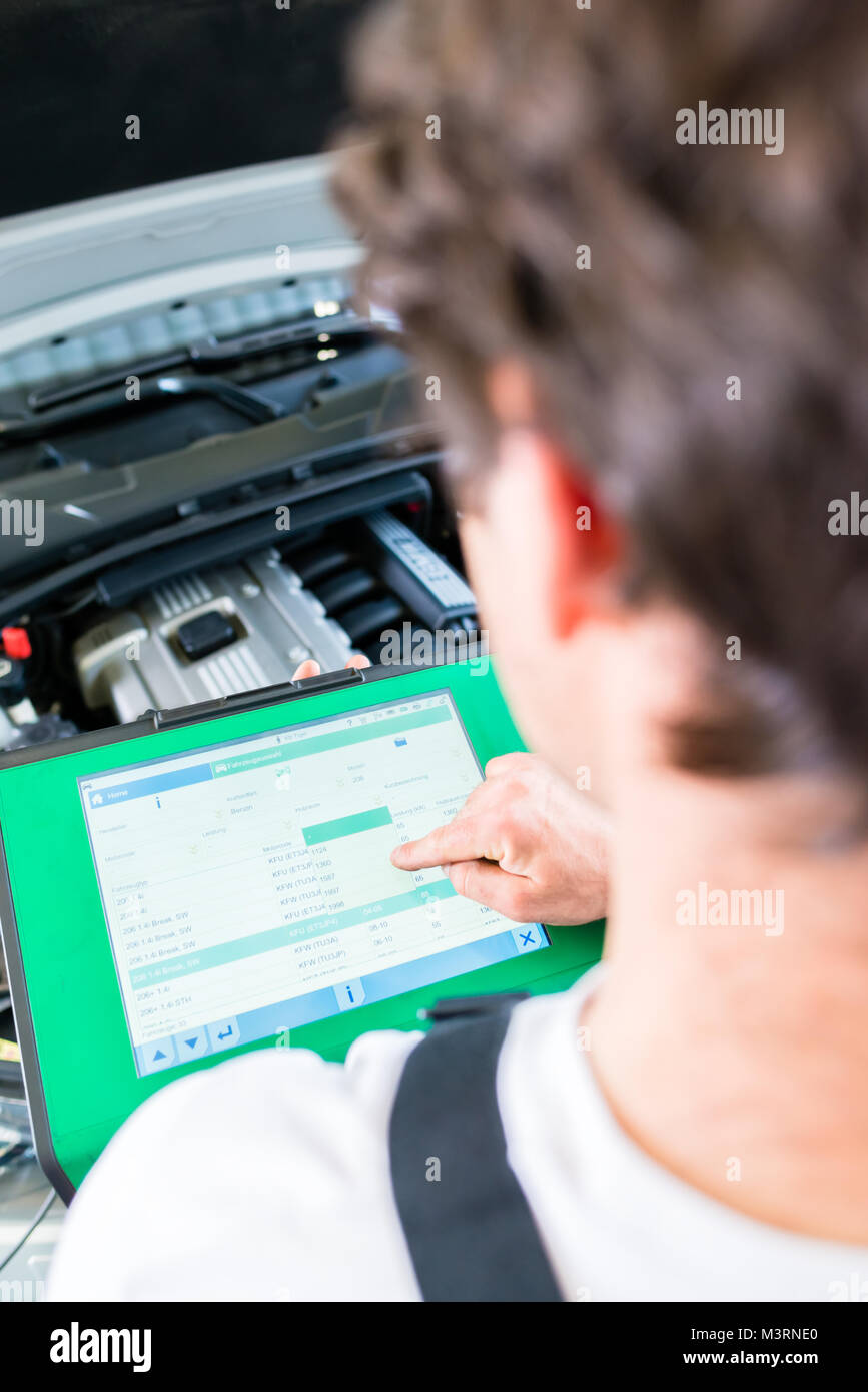 Mécanicien avec outil de diagnostic en atelier voiture Banque D'Images Mécanicien avec outil de diagnostic en atelier voiture Banque D'Images