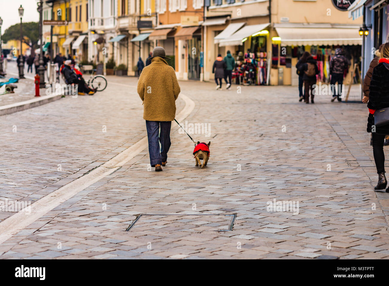 Classy young lady walking with dog in sea village italien Banque D'Images