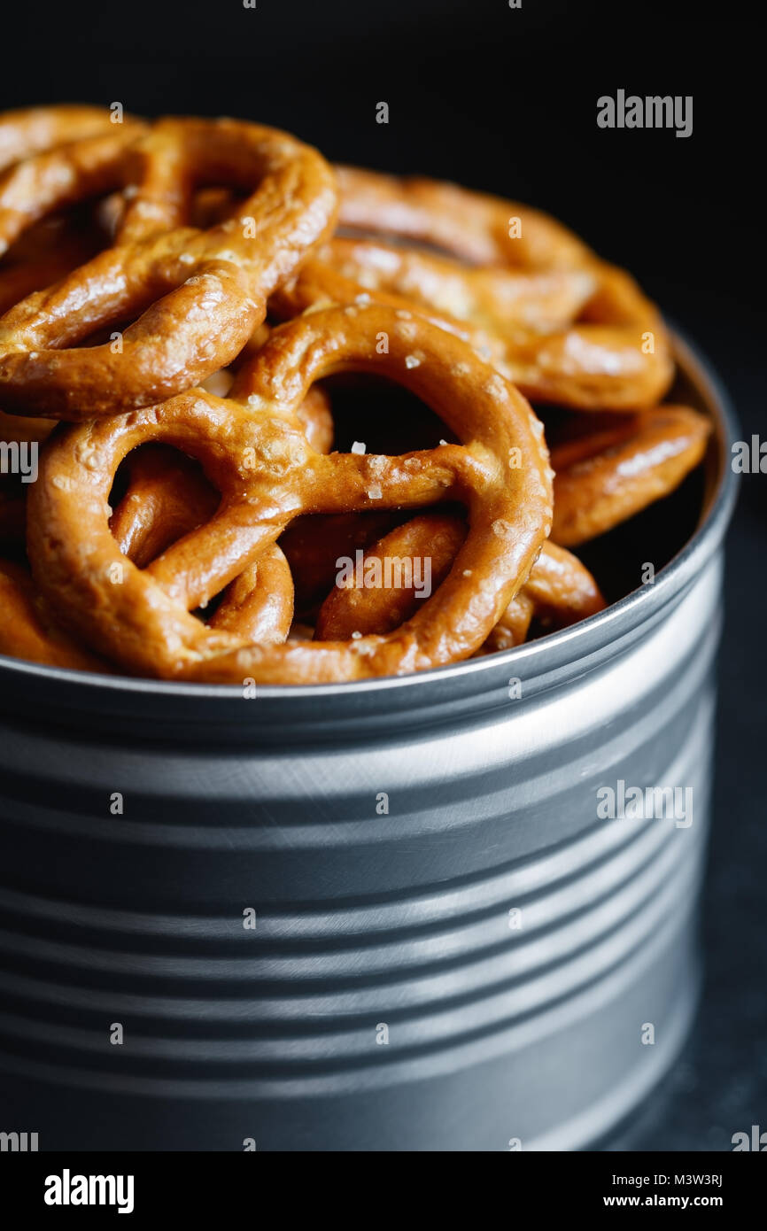 Bretzels croustillants apéritif dans un pot en métal sur un tableau noir. Lumière mystique style. Banque D'Images